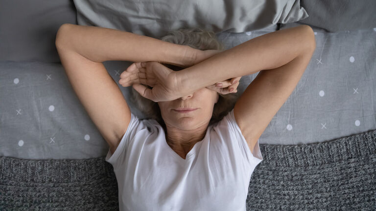 Top view aged woman lying on bed suffers from insomnia