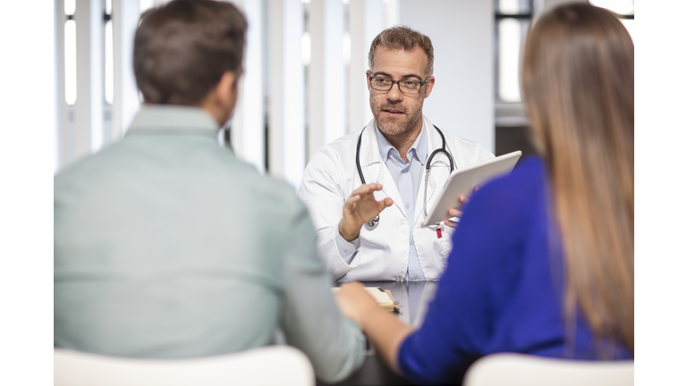 Doctor talking to couple in medical practice