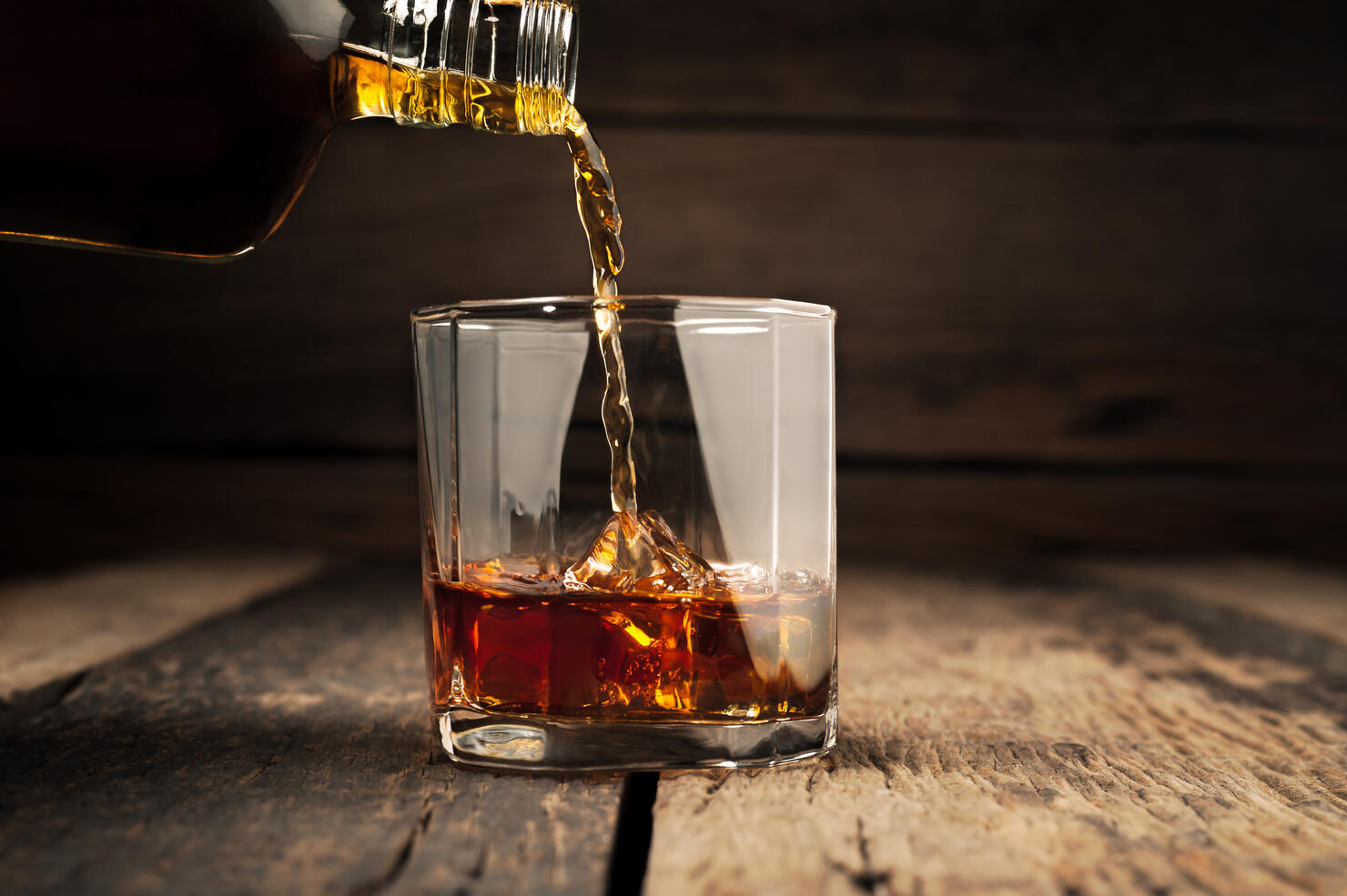 Pouring glass of whiskey, Close-up whisky on the rocks.