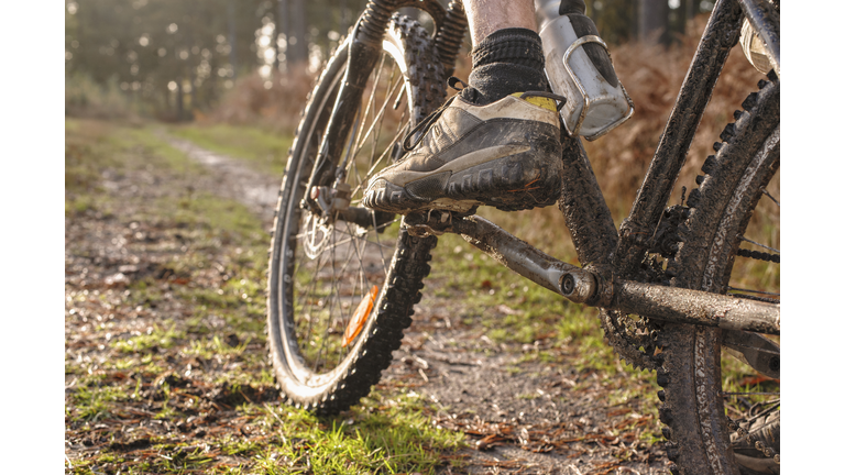 Close up of Caucasian man's muddy foot on mountain bike