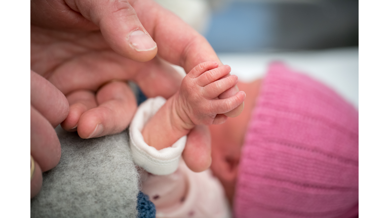 Newborn baby holding on to a finger