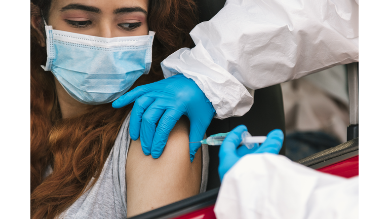 Nurse applying vaccine to patient in car