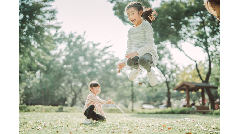 Young family jumping ropes joyfully on the lawn