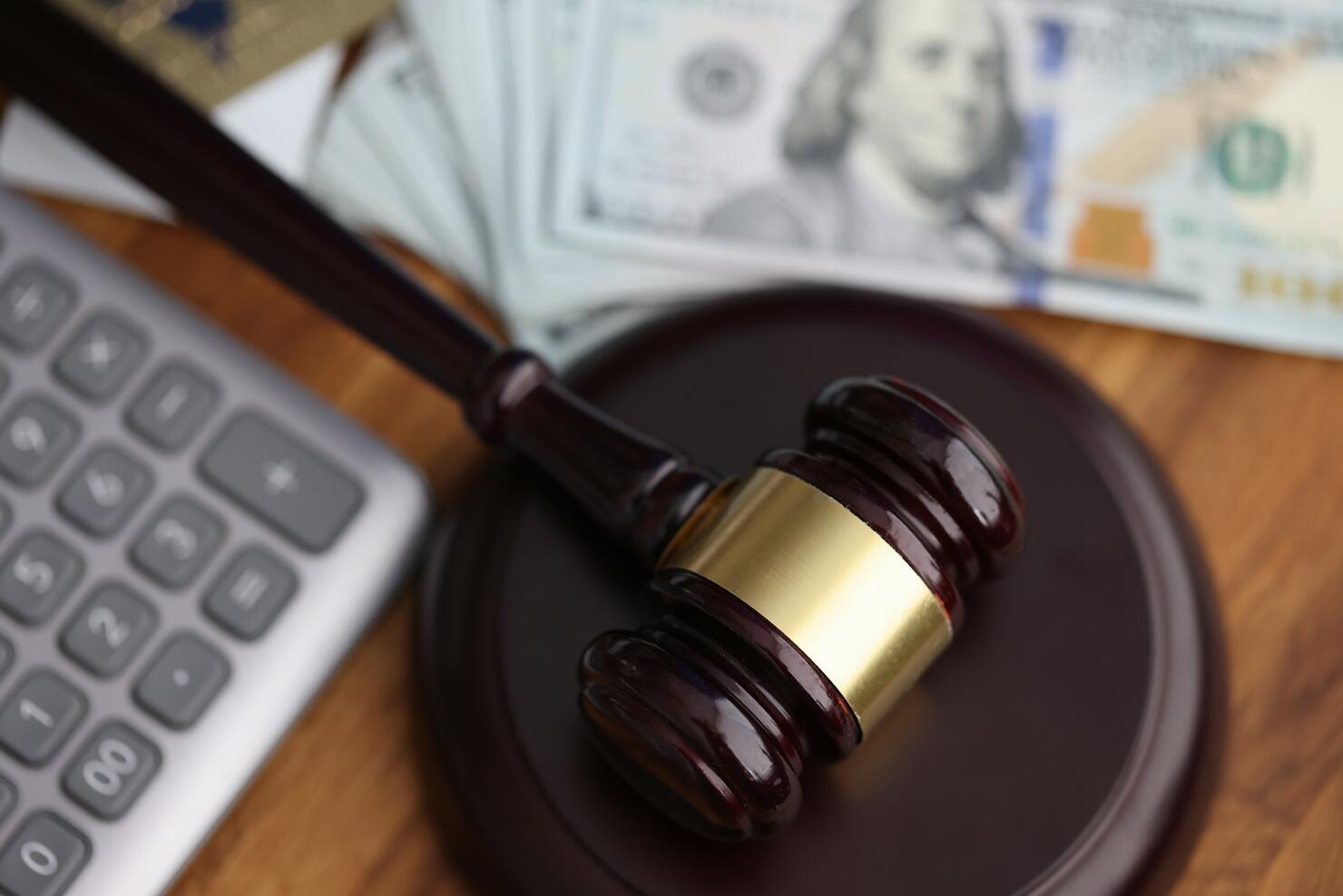 Hammer, american dollars, calculator lie on table in courthouse close-up