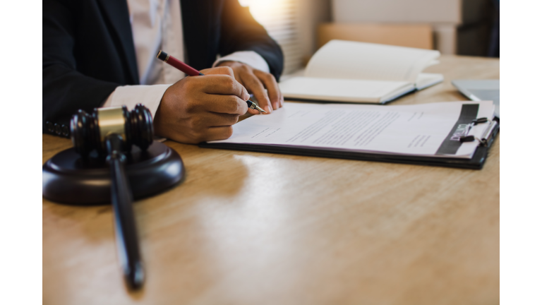 hand of business people sign contract with justice hummer on table