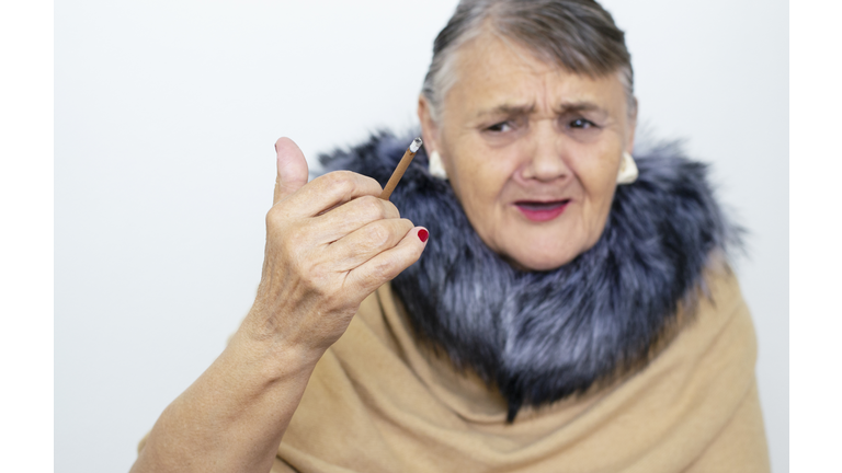 The fashionable old lady doesn't want to smoke. Grandma is a hipster against cigarettes and Smoking. Mature lady with a cigar.