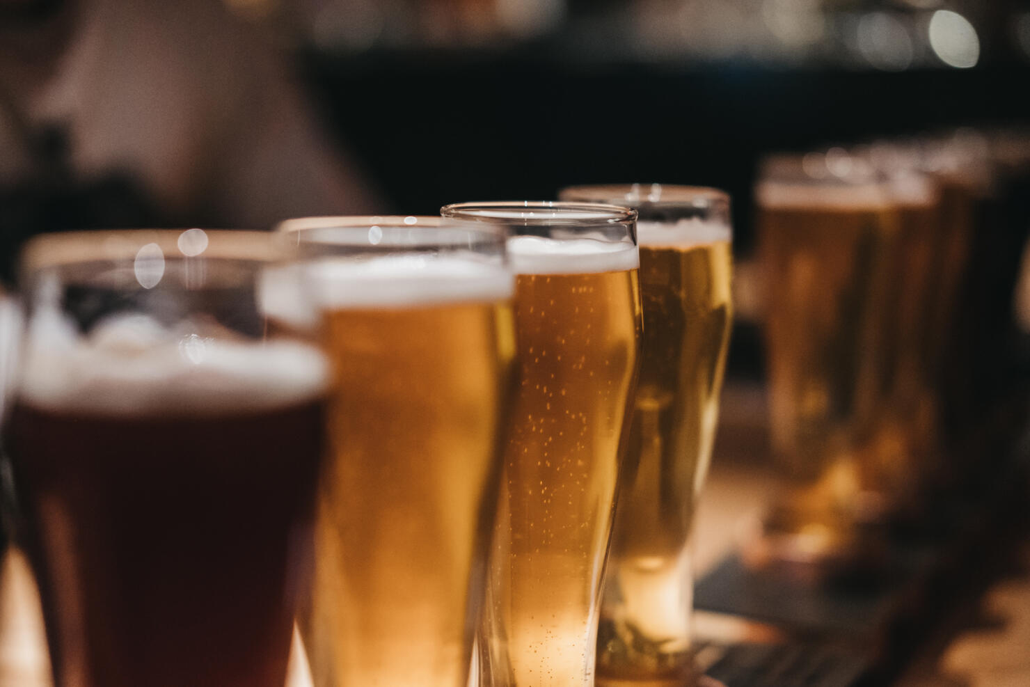 Close up of a rack of different kinds of beers, dark to light, on a table.