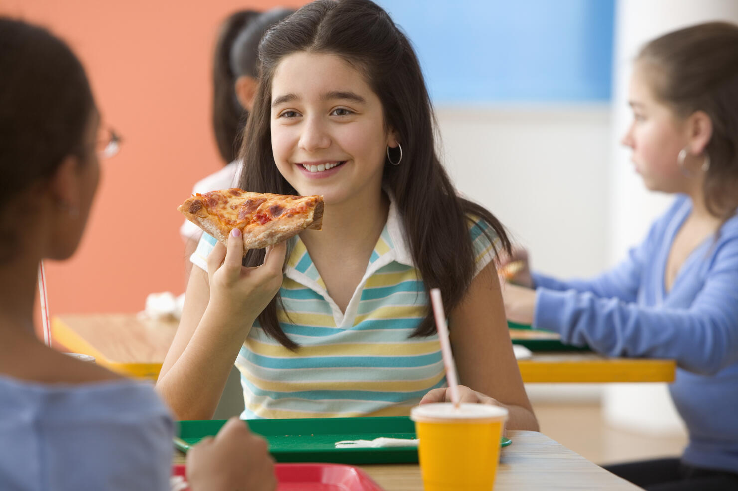 Four girls eating pizza in cafeteria