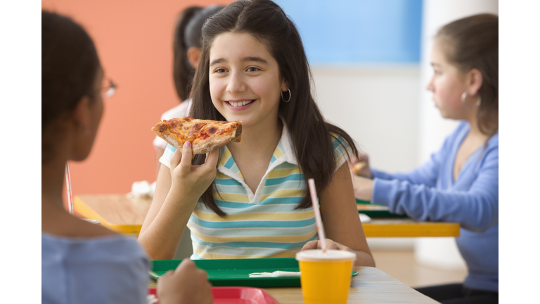 Four girls eating pizza in cafeteria