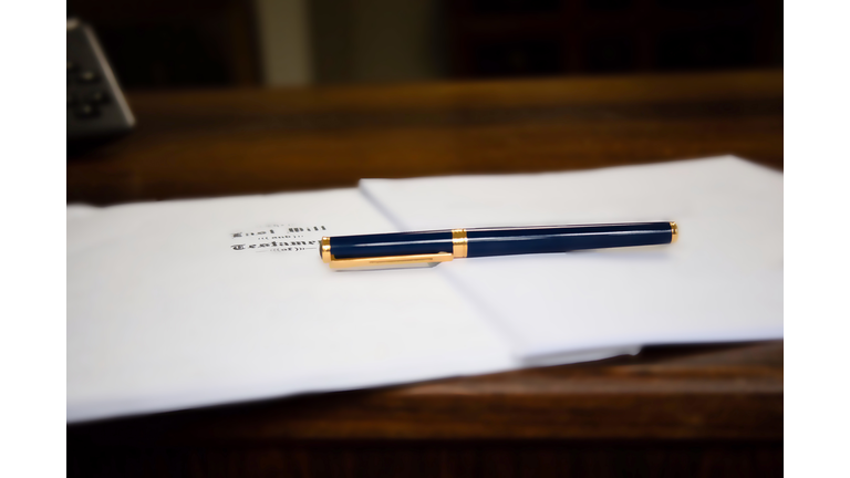 last will & testament & other estate planning documents on wooden desk under pen