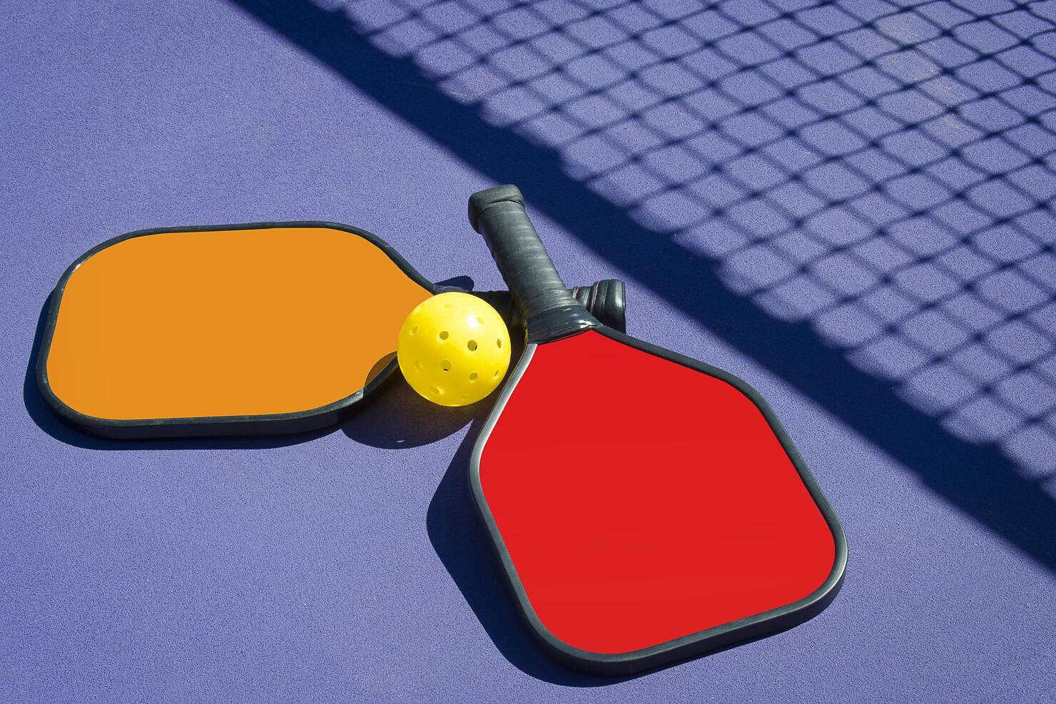 Pickleball - Two Paddles and A Ball in Net Shadow