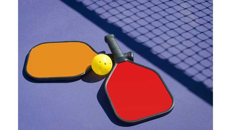 Pickleball - Two Paddles and A Ball in Net Shadow