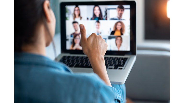 Business woman making video call and showing thumb up to laptop on the online briefing while sit on sofa at home.