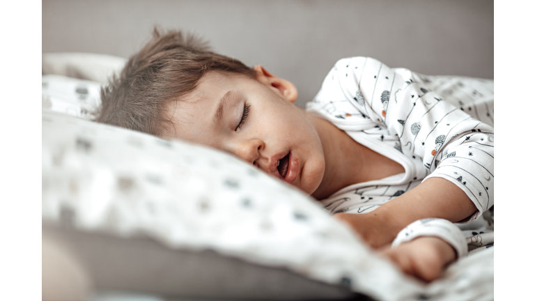 Little blond boy sleeping in his bed.