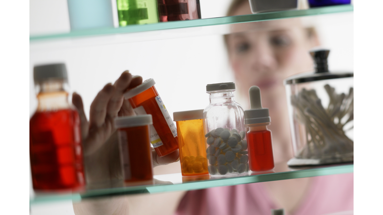 Woman taking pills from medicine cabinet