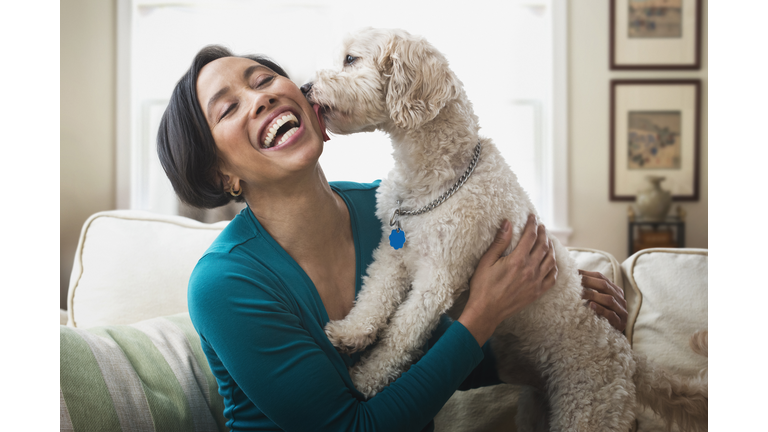 Black woman petting dog on sofa