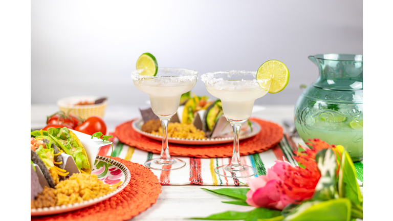 Margarita glasses with salted rim and lime and plates of tacos