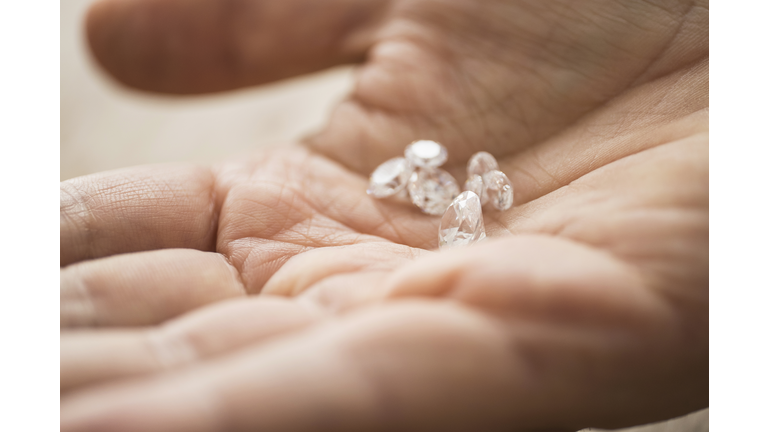 Close up of mans hand holding diamonds