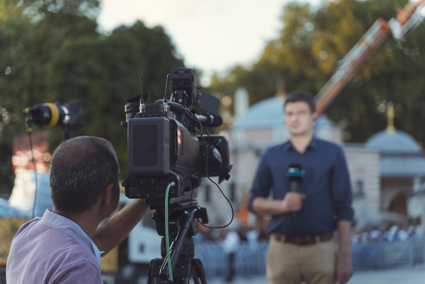 Behind the scene concept. Cameraman working on professional camera taking TV interviewer, professional news reporter making news outdoors.
