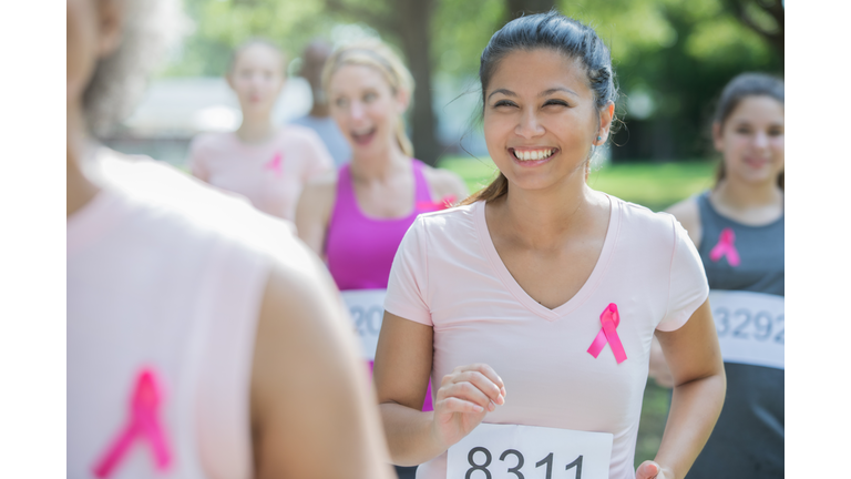 Asian American woman smiles while running charity race to benefit breast cancer research