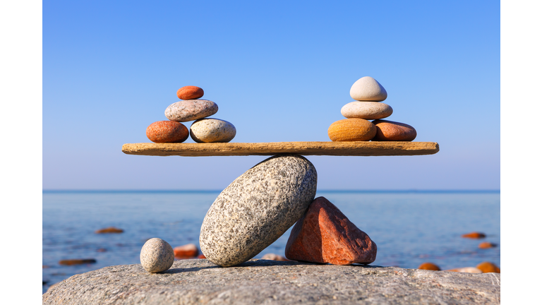 Symbolic scales of the stones against the sea. Pros and cons concept