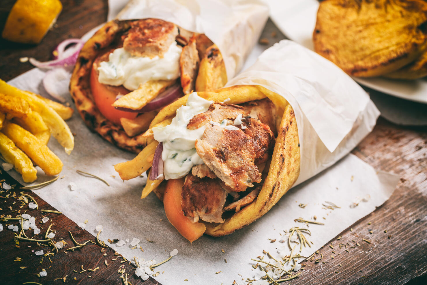 Greek gyros wraped in a pita bread on a wooden background