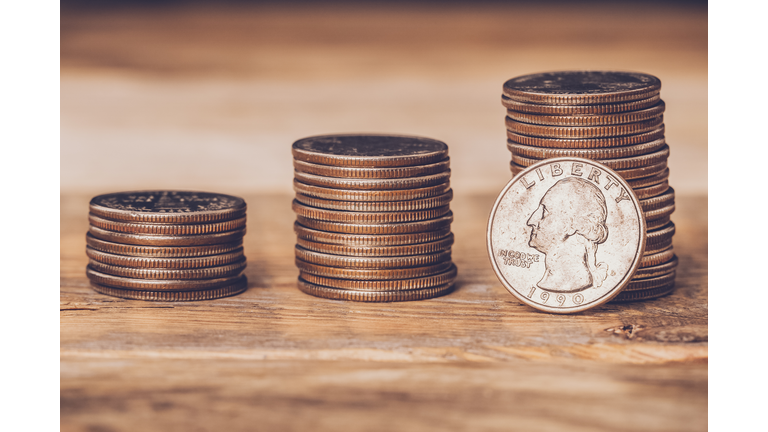 Closeup of three american quarters stacks with a coin on the face side standing against the highest pile. Free trade, economy, liberalism, capitalism concepts.