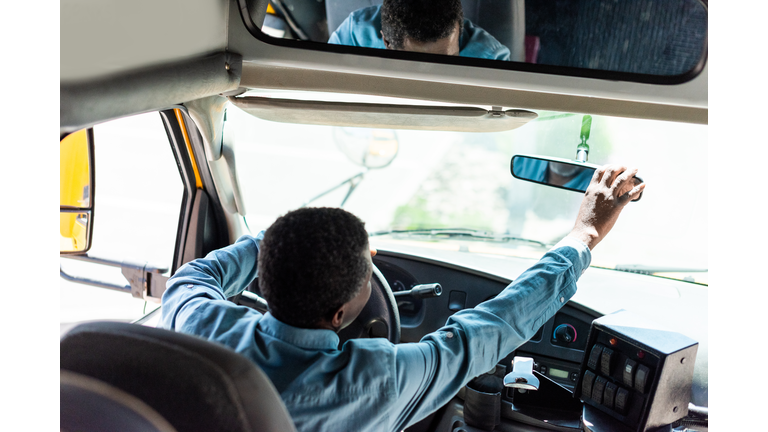 mature african american driver adjusting back view mirror at bus