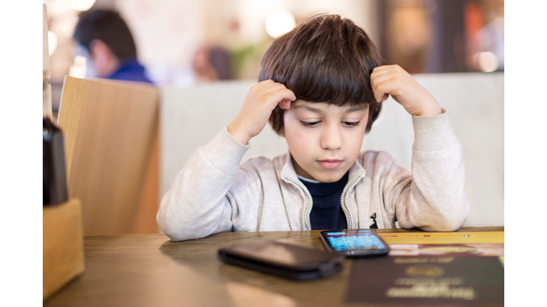 Boy looking at smartphone in a restaurant