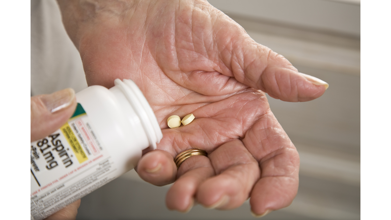 senior woman with distorted arthritis hand taking aspirin pills