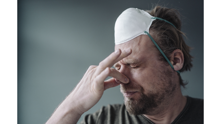 Portrait of man with protective mask holding nose