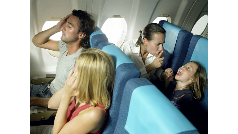 Girl (5-7) yelling behind young couple in airplane