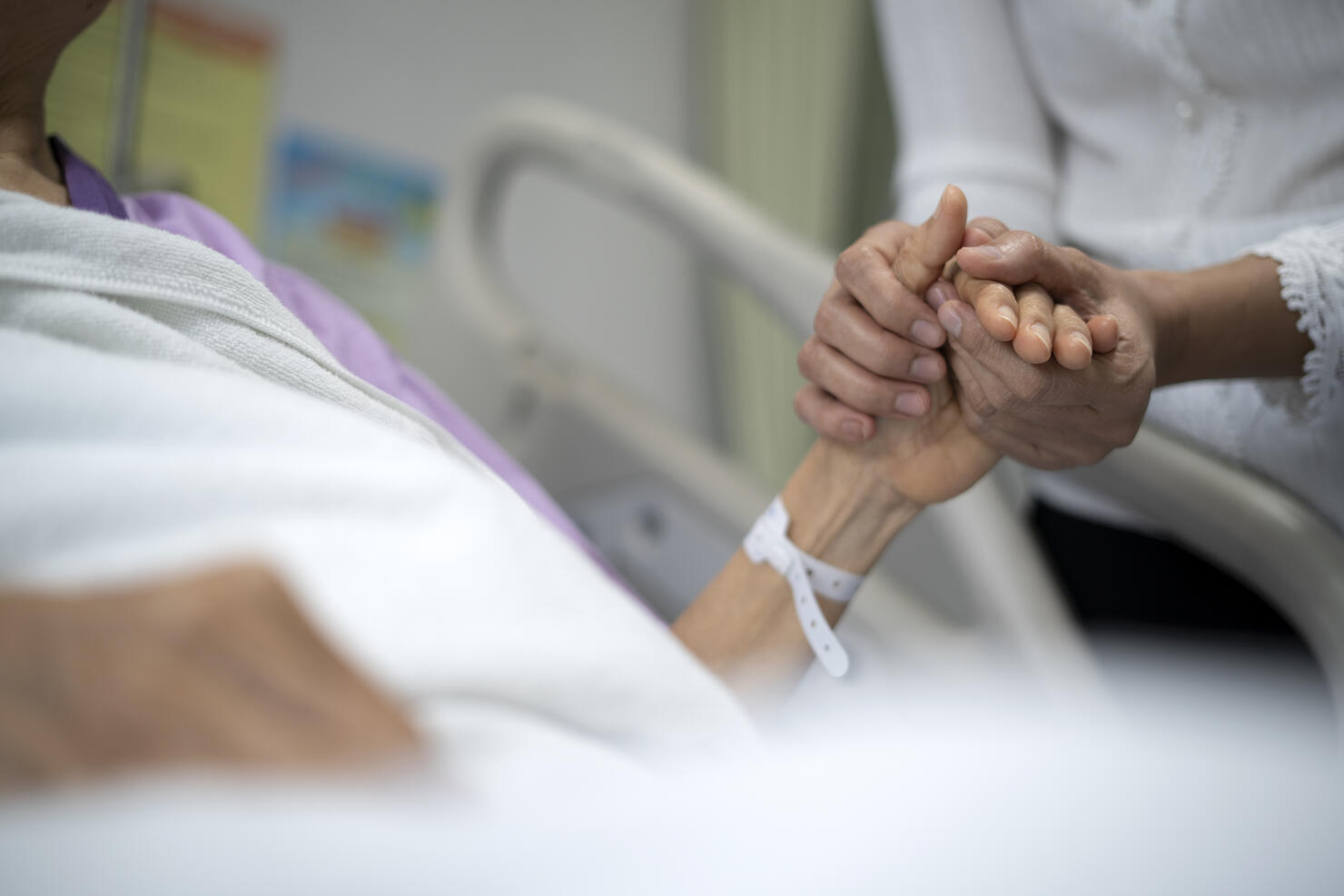 Shot of daughter encourage her mother and holding the mother's hand to sleep on the bed ​in hospital.