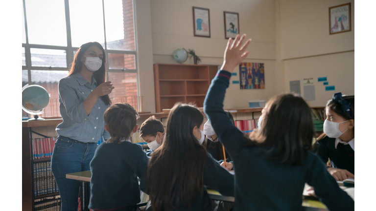 Teacher and students wearing facemasks in class at the  school