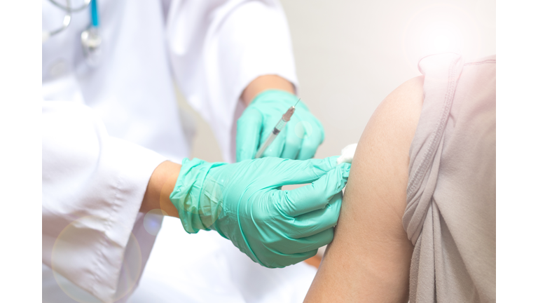 Vaccination healthcare concept. Hands of doctor or nurse in medical gloves injecting a shot of vaccine to a man patient