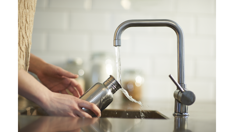 Cleaning a plastic free reusable water bottle in kitchen sink.