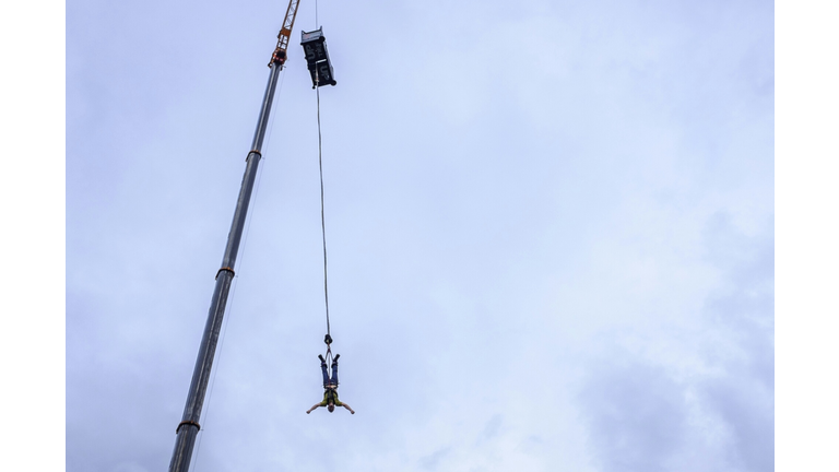 Low Angle View Of Man Bungee Jumping From Crane Against Sky