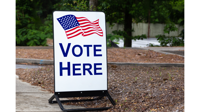 Vote here sign with an American flag to vote for elected government officials.