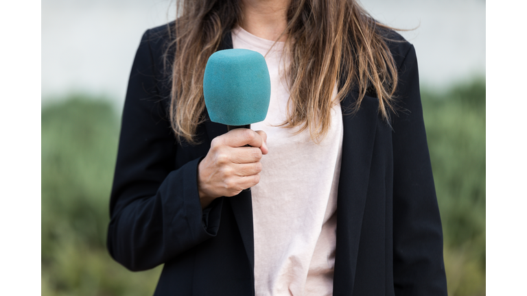 Close-up of journalist woman holding a microphone - stock photo