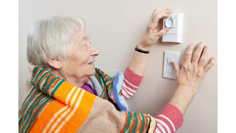 Senior woman adjusting her thermostat