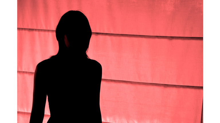 Silhouetted view of woman standing at red light district