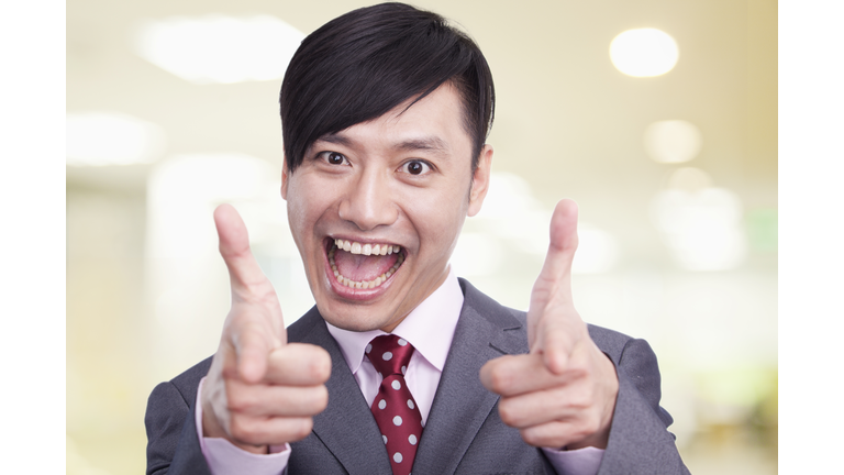 Young businessman making pistols with his fingers at camera, portrait