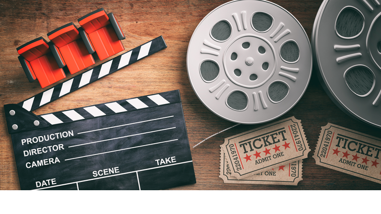 Film reels with retro cinema tickets, movie clapper and red theater seats on wooden background. 3d illustration.
