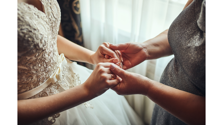 Bride on wedding day holding her mother's hands. Concept of relationship between moms and daughters