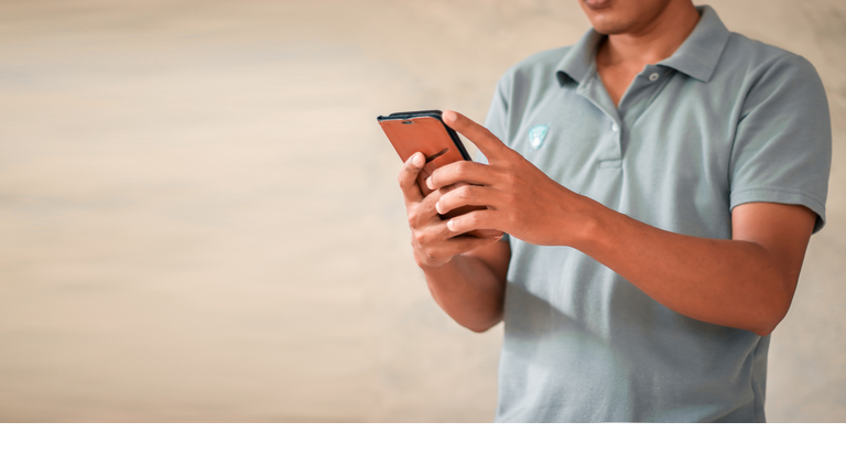 Man using smartphone on gray background.