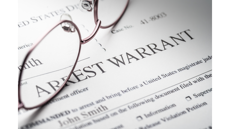 Arrest Warrant document with reading glasses