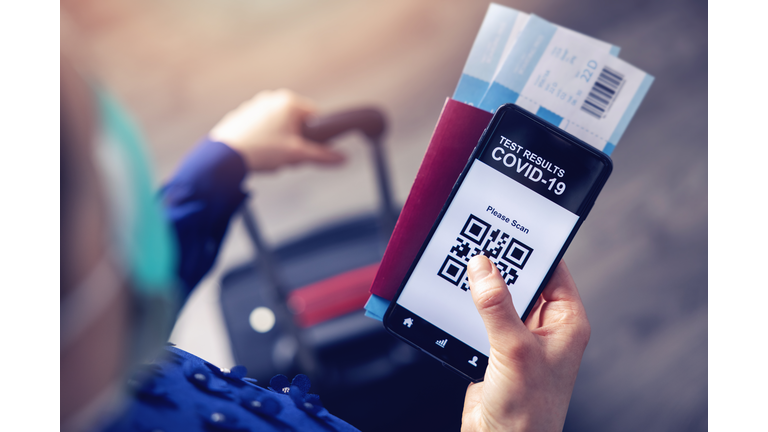 person in airport using mobile app in phone to show covid-19 test results for travel