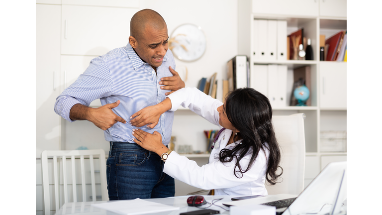 Female doctor palpating abdomen of patient in medical office