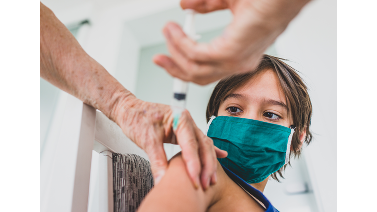 Little boy being vaccinate at senior doctor's office