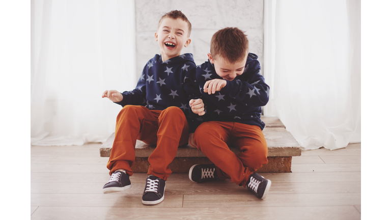 Happy Siblings Sitting On Floor At Home